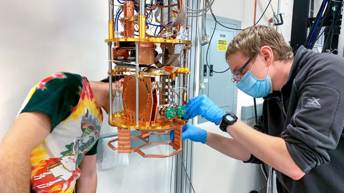 Doctoral candidates Zachary Huber, left, and Ben Keller install detector array components for the Simons Observatory in one of the dilution refrigerators in Michael Niemack’s laboratory.