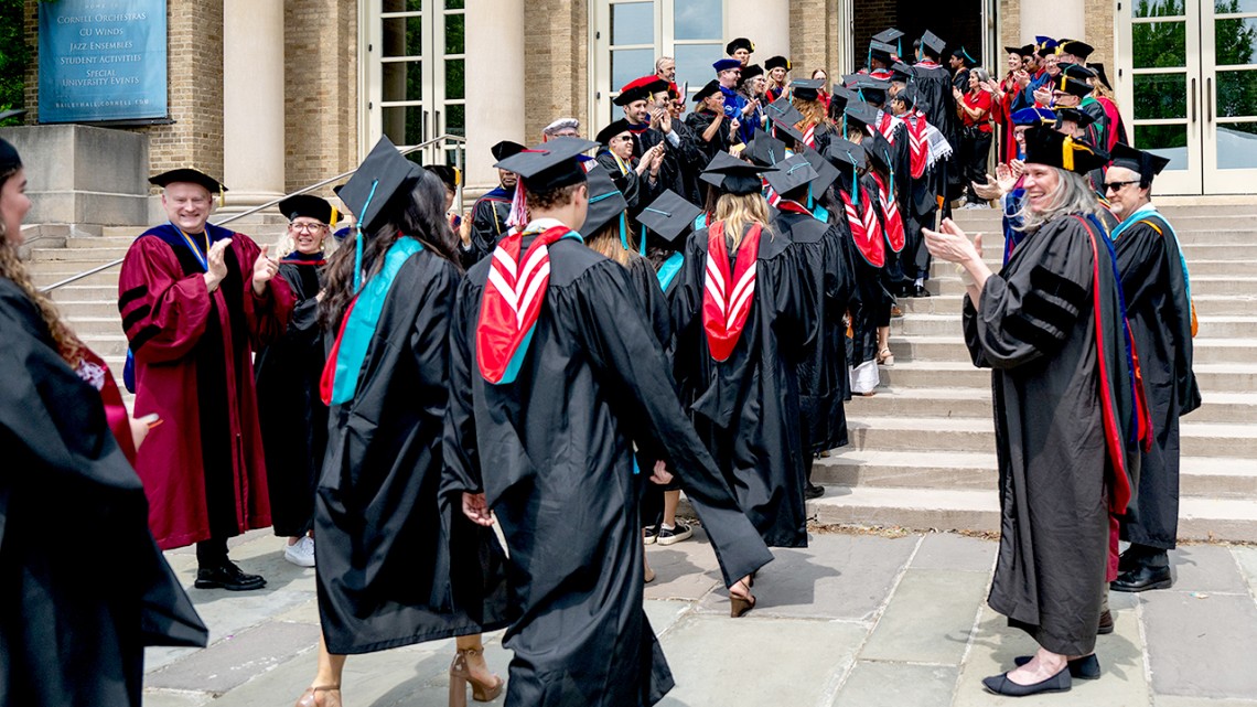 The Cornell Jeb E. Brooks School of Public Policy’s faculty cheer as members of the school’s third graduating class file into Bailey Hall for their commencement ceremony.