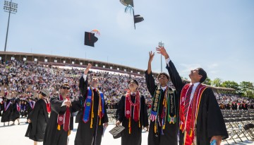 A small group of graduates throwing their caps in the air. 