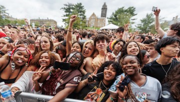 A crowd of college students taking selfies and throwing hand signals. 